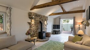 A cozy living room with a stone fireplace, a television, and comfortable seating. - The Old Rectory Cottage (Tothill, near Louth)