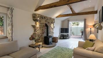 Una sala de estar acogedora con chimenea de piedra, televisor y asientos cómodos.