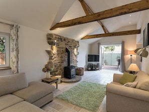 A cozy living room with a stone fireplace, a television, and comfortable seating. - The Old Rectory Cottage (Tothill, near Louth)