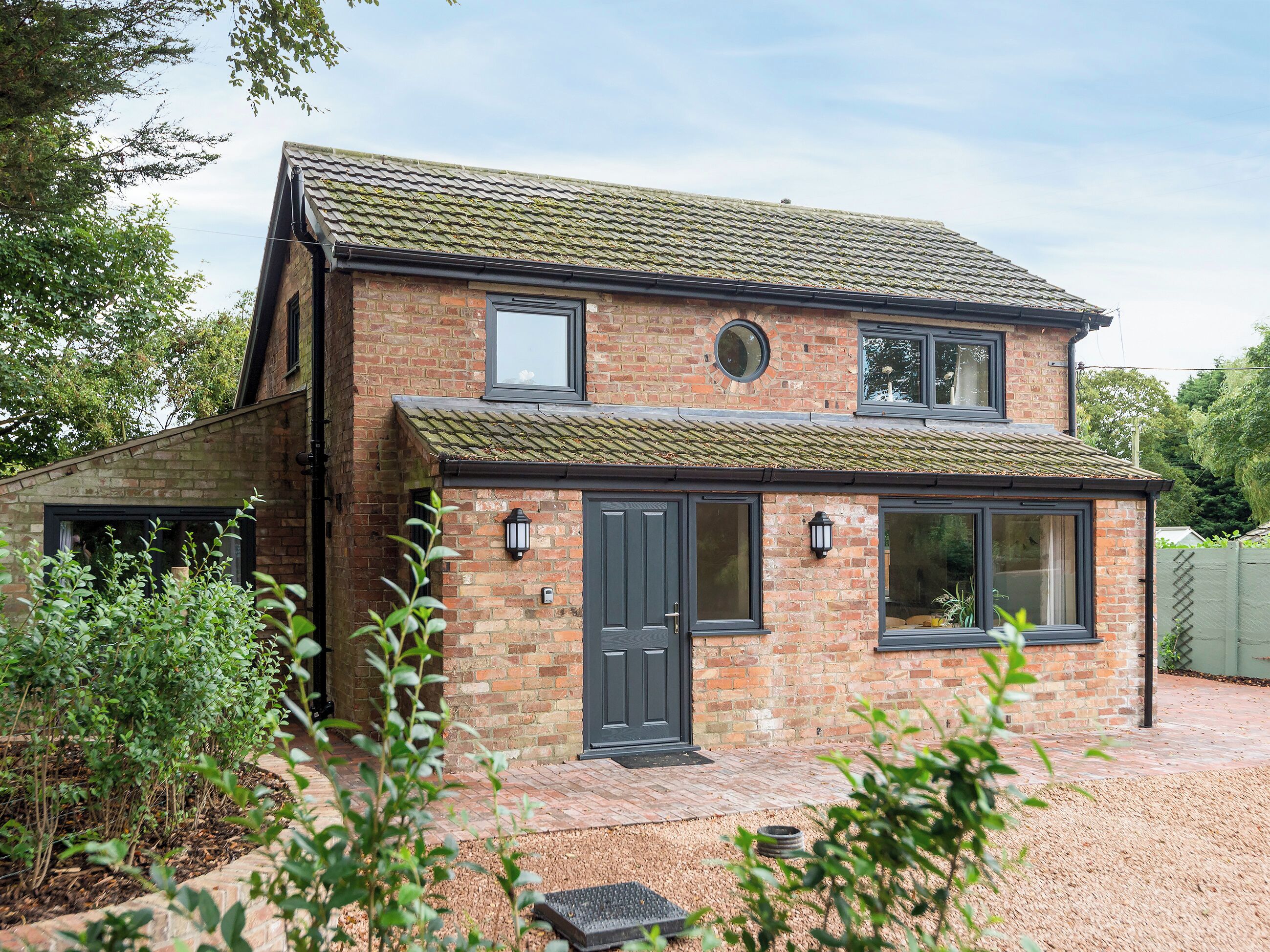 A two-story house with a brick facade, a tiled roof, and a front door with a window above it.