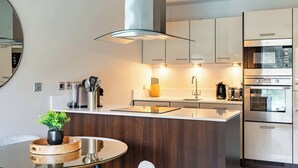 Una cocina moderna con una isla central, electrodomésticos integrados y una mesa de comedor redonda.