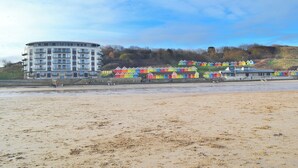 A coastal building with a circular structure and colorful beach huts in the background. - North Bay Sands Apartment 2- UK2630 (Scarborough)