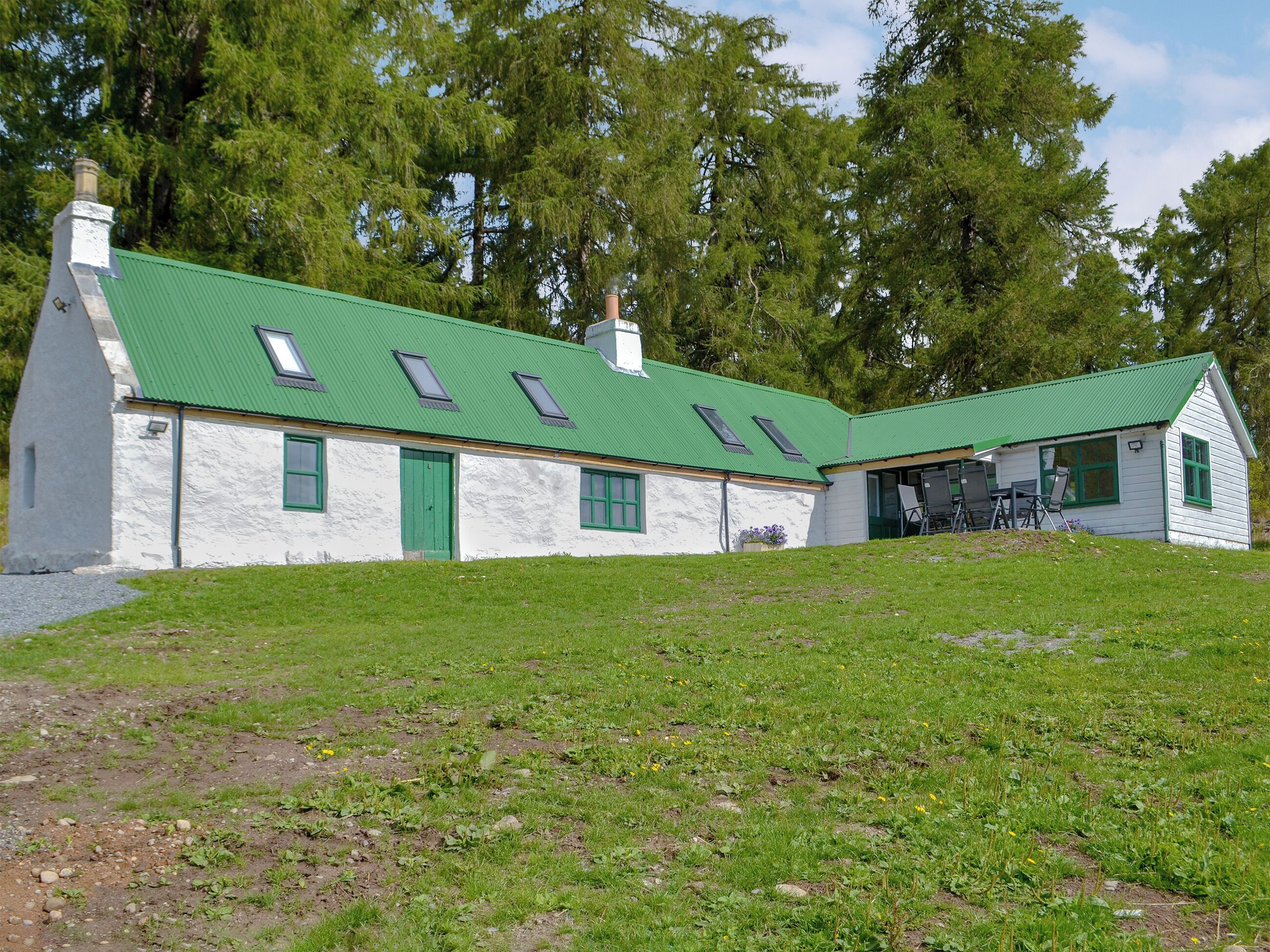 A white building with a green roof and multiple windows.