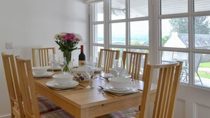 A dining table set for six with white plates, bowls, and wine glasses, surrounded by plaid-patterned chairs.