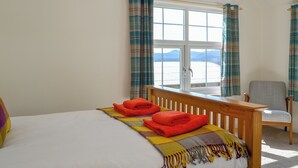A hotel room with a bed, a chair, and a window with curtains.