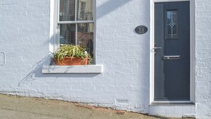 A white brick building with a dark door and a window with a potted plant. - 2 bedroom accommodation in Scarborough (Scarborough)