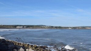 A coastal view with a rocky shoreline, a clear sky, and distant buildings. - 2 bedroom accommodation in Scarborough (Scarborough)