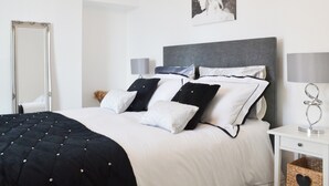 A neatly arranged bedroom with a large bed, a bedside table with a lamp, and a wall-mounted picture. - 2 bedroom accommodation in Scarborough (Scarborough)