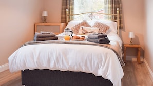 Un lit bien fait, avec des oreillers, une table de chevet avec une lampe et une fenêtre avec des rideaux.