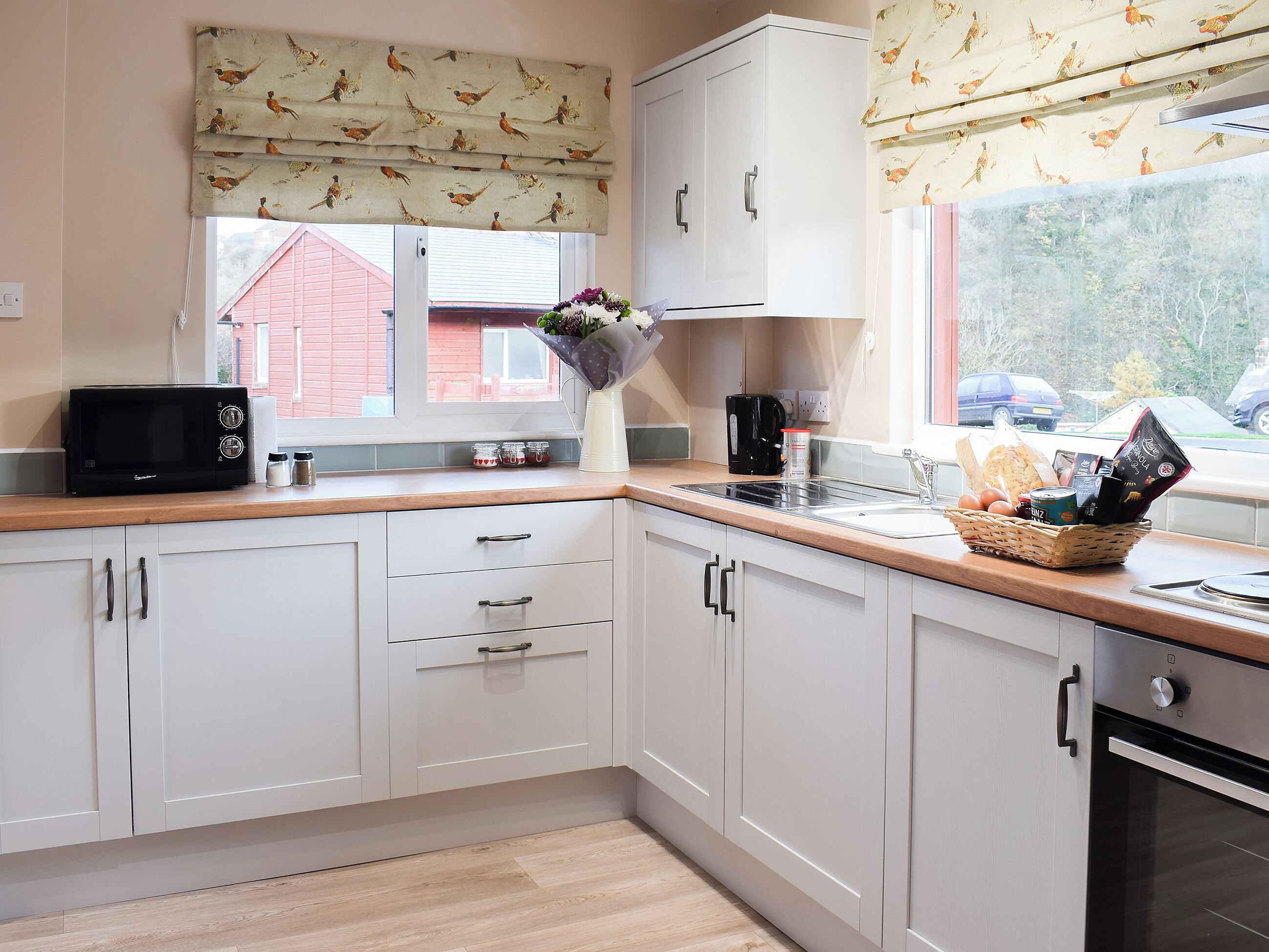 A modern kitchen with white cabinets, a microwave, a sink, and a window with a view of the outside.
