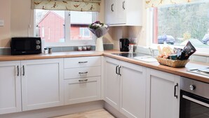 Une cuisine moderne avec des meubles blancs, un four à micro-ondes, un évier et une fenêtre donnant sur l’extérieur.