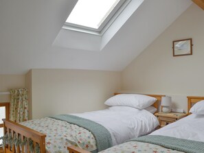 A bedroom with two beds, a skylight, a nightstand with a lamp, and a framed picture on the wall. - The Stables - UKC3749 (Charmouth, near Lyme Regis)
