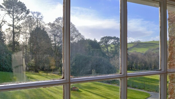 A view through a window with a clear sky, a green lawn, and trees in the background. - 2 bedroom accommodation in Lostwithiel (Lostwithiel)
