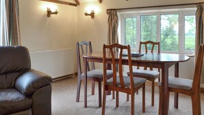 Un coin repas avec une table ronde, six chaises en bois et un canapé en cuir.