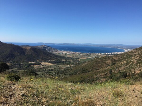 Paisaje costero con un pueblo en el valle, terreno montañoso y cielo despejado.