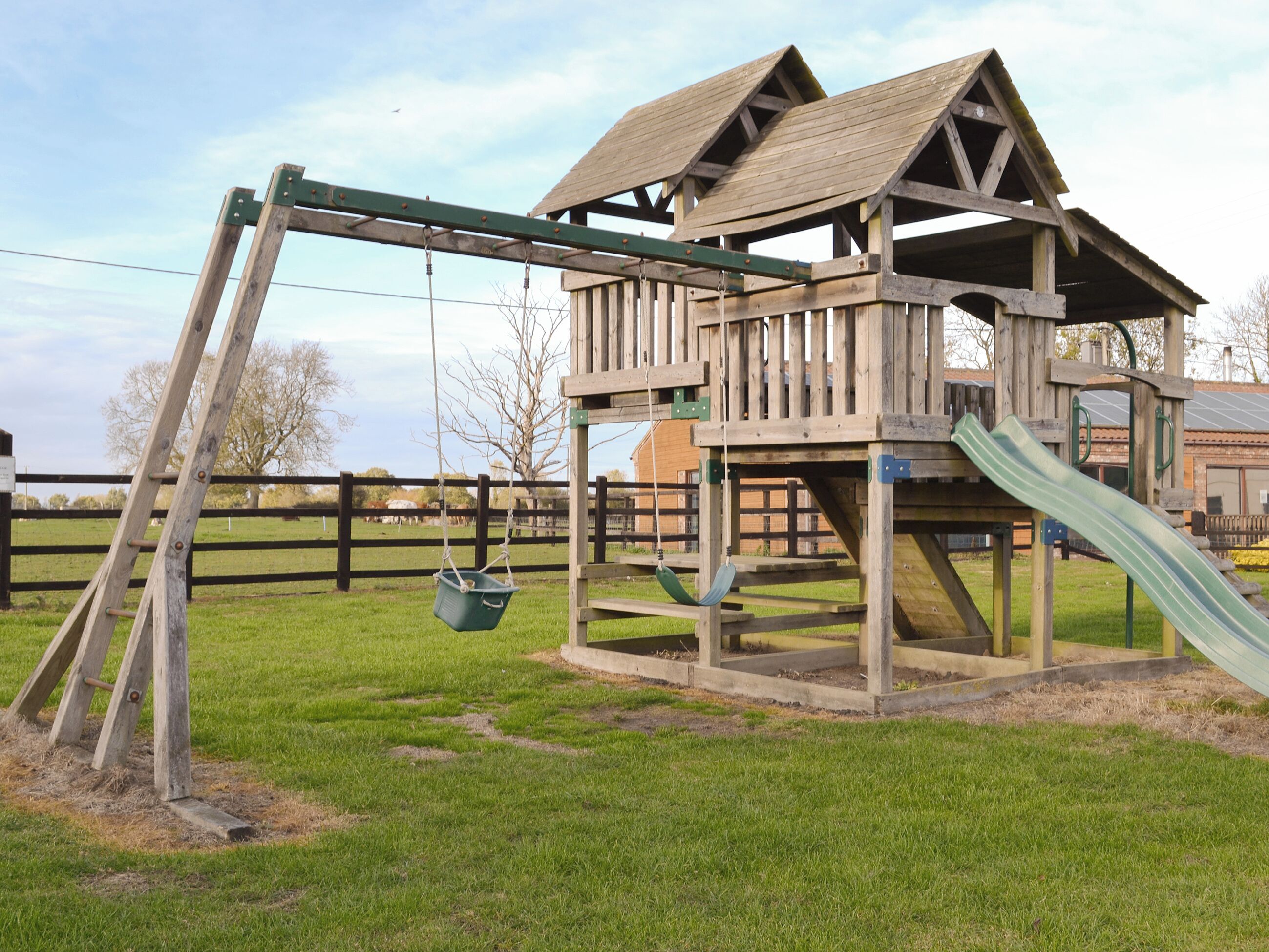 Une structure de jeux en bois comprenant une balançoire et un toboggan.