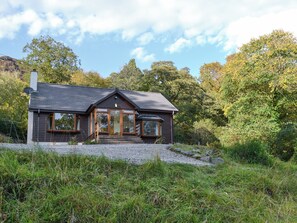 Une maison moderne avec un toit en pente, de grandes fenêtres et une façade en bois.
