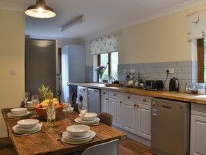 A well-lit kitchen with a dining table set for four, a washing machine, and a coffee maker. - Look out over the sparkling loch and watch the abundant wildlife. (Camus Inas, Salen, near Acharacle)