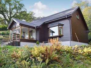 A modern house with a sloped roof, large windows, and a wooden deck.