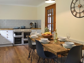 A modern kitchen with white cabinets, a wooden countertop, and a dining area with a wooden table and chairs.