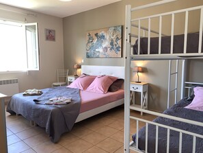 A bedroom with a bed, two bedside tables with lamps, a chair, a radiator, and a window.