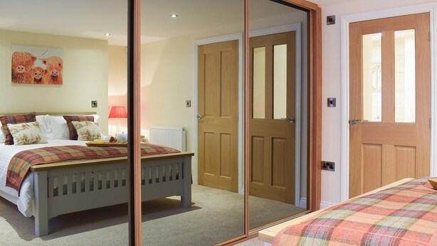 A bedroom with a bed, a mirror, and a door. - 2 bedroom accommodation in Sleights, near Whitby (Sleights, near Whitby)