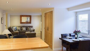 A modern living room with a sofa, a dining table with chairs, and a kitchen area with a counter. - 2 bedroom accommodation in Sleights, near Whitby (Sleights, near Whitby)