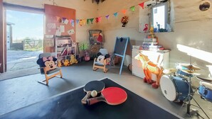 A room with a ping pong table, a drum set, shelves with stuffed toys, and a window with a view. - 3 bedroom accommodation in Uplawmoor, near Barrhead (Uplawmoor, near Barrhead)