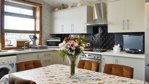 A kitchen with a dining table, chairs, a sink, a stove, and a television. - 3 bedroom accommodation in Uplawmoor, near Barrhead (Uplawmoor, near Barrhead)