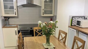 Une cuisine moderne avec une table en bois, des chaises, un vase de fleurs et un four à micro-ondes.