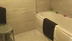 Une salle de bain avec une baignoire, une petite table ronde et une serviette accrochée au mur.
