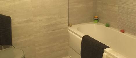 A bathroom with a bathtub, a small round table, and a towel hanging on the wall.