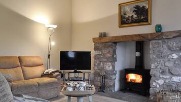 A cozy living room with a stone fireplace, a flat-screen TV, and a comfortable sofa.