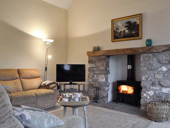 A cozy living room with a stone fireplace, a flat-screen TV, and a comfortable sofa.