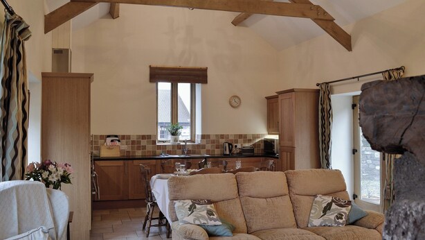 A spacious kitchen with wooden beams, a dining area with a table set for four, and a cozy seating area with a sofa. - 3 bedroom accommodation in Middleton, near Swansea (Middleton, near Swansea)