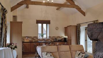 A spacious kitchen with wooden beams, a dining area with a table set for four, and a cozy seating area with a sofa.