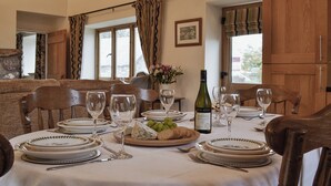A dining table set with plates, glasses, and a bottle of wine. - 3 bedroom accommodation in Middleton, near Swansea (Middleton, near Swansea)