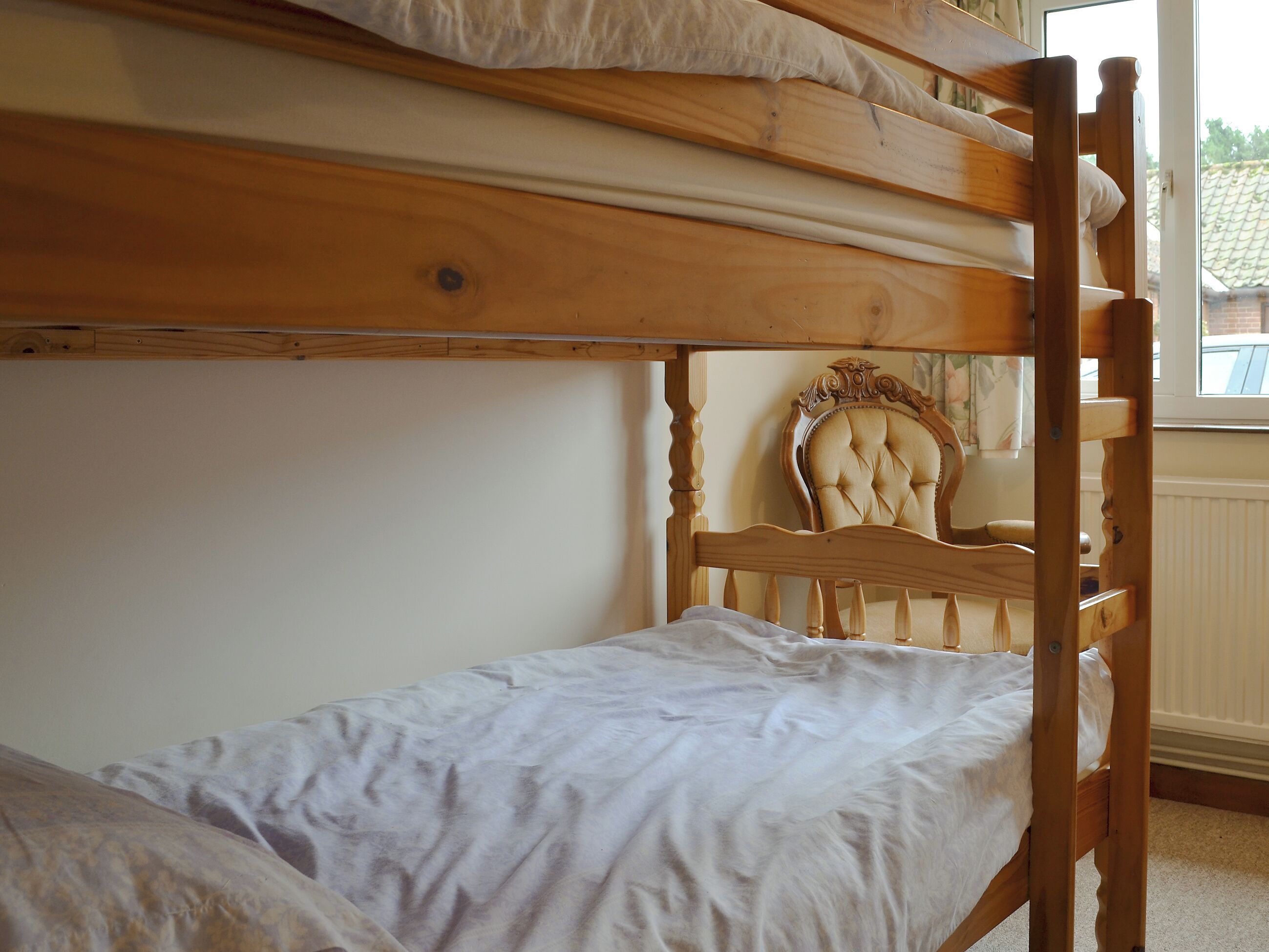 A bunk bed with a wooden headboard and a single bed below.