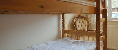A bunk bed with a wooden headboard and a single bed below.
