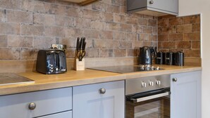 Een moderne keuken met een metselwerk spatwand, roestvrijstalen apparatuur en houten aanrechtbladen.