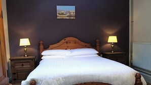 A neatly made bed with white linens, two bedside tables with lamps, a wooden headboard, and a framed picture on the wall. - 1 bedroom accommodation in Fitling, near Hull (Fitling, near Hull)