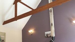 A room with exposed wooden beams, a white ceiling, and a purple wall. There is a light fixture and a framed picture on the wall. - 1 bedroom accommodation in Fitling, near Hull (Fitling, near Hull)