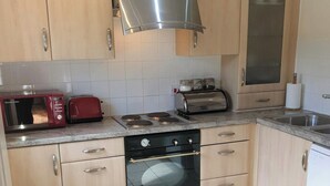 A compact kitchen with a microwave, toaster, stove, oven, and a sink. - 1 bedroom accommodation in Fitling, near Hull (Fitling, near Hull)