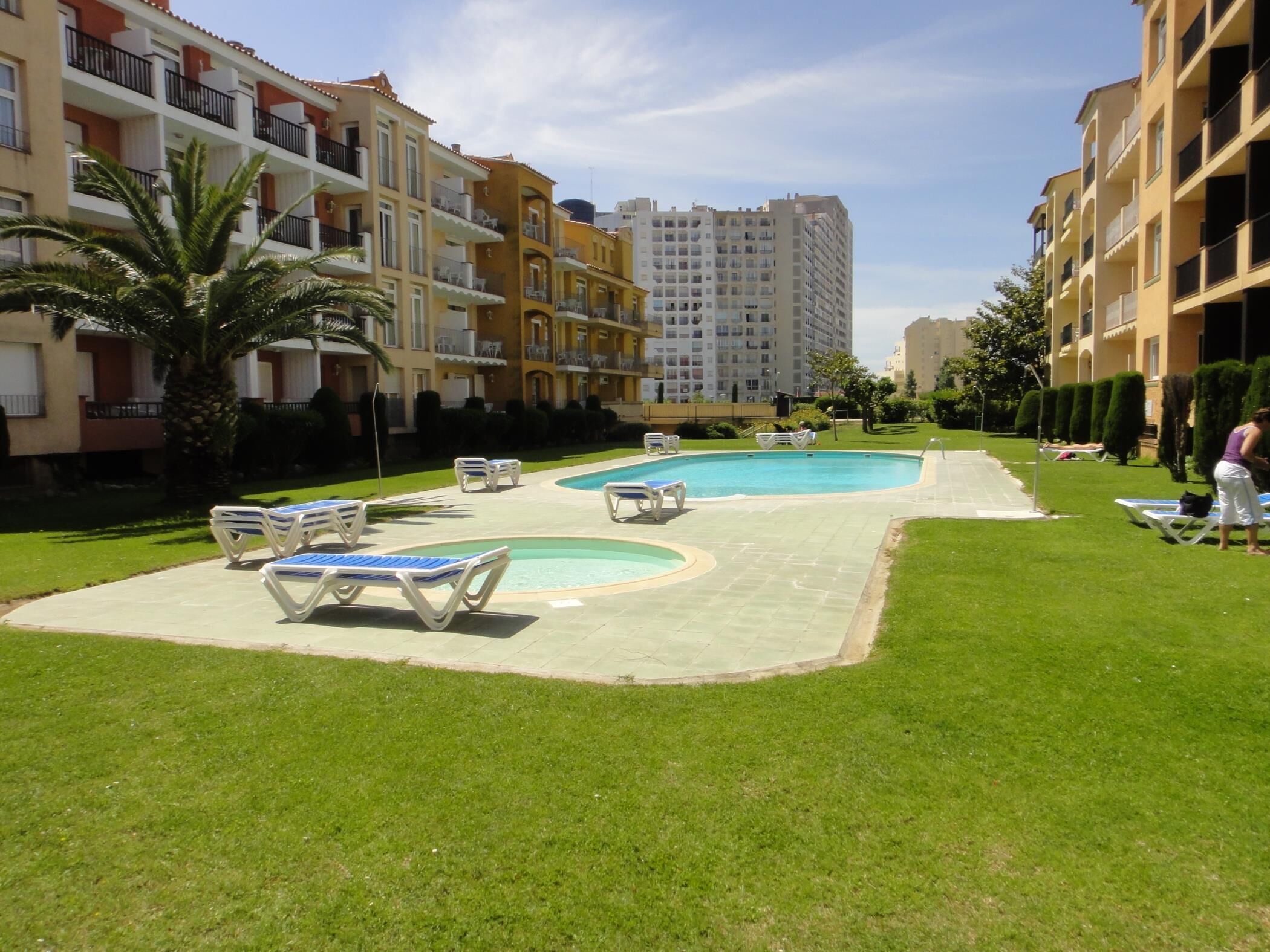 A pool area with lounge chairs and a building in the background.