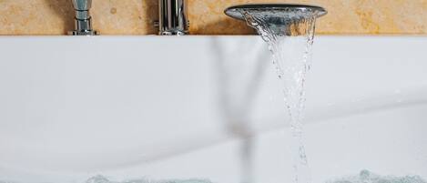 A bathroom with a bathtub, a showerhead, and a faucet.
