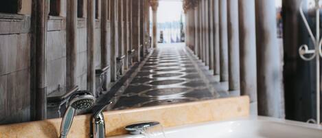 A long corridor with columns leading to a bathtub with running water.