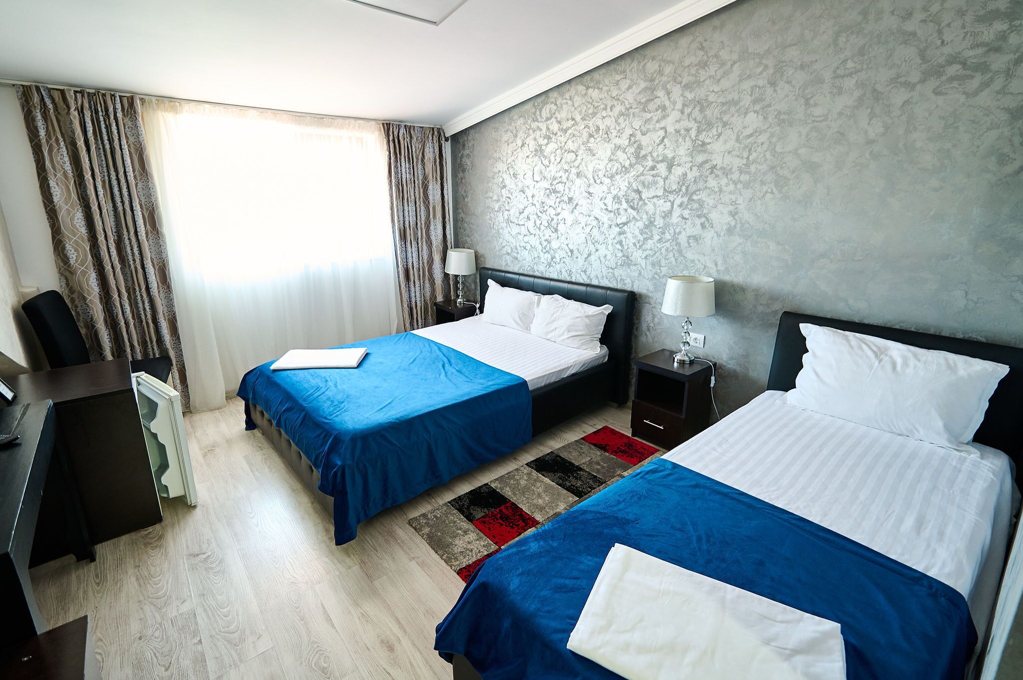 A hotel room with two beds, a desk, and a chair.