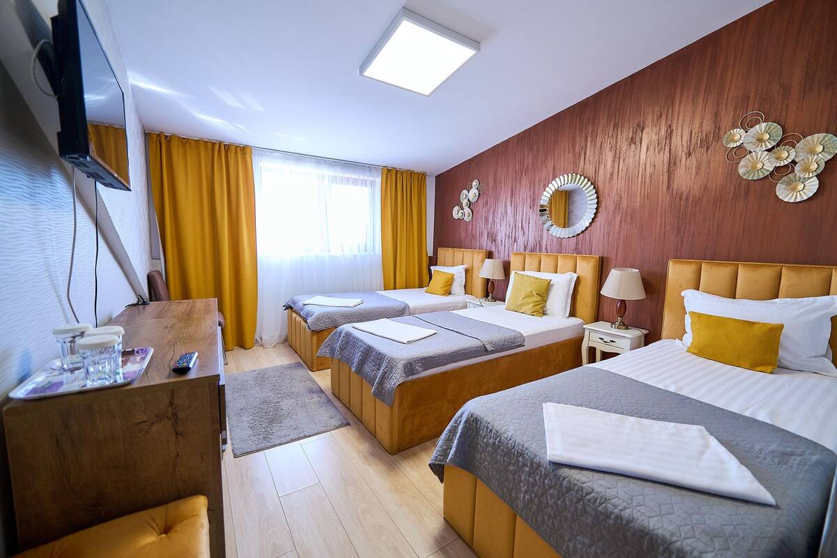 Een hotelkamer met drie bedden, een bureau en een televisie.