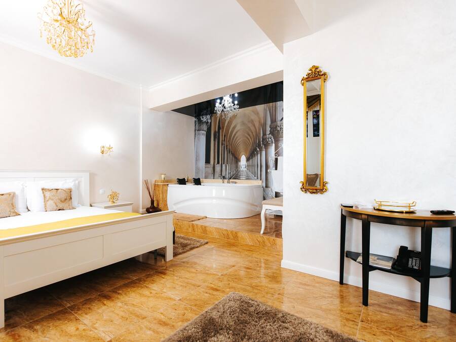 A spacious bedroom with a large bed, a separate bathroom with a bathtub, and a vanity with a mirror.