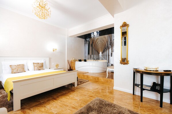 A spacious bedroom with a large bed, a separate bathroom with a bathtub, and a vanity with a mirror. - Evianne Boutique Hotel (Galati)